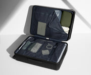 The Large suitcase in Jet Black shown open on its side and packed with Away's packing organizers to show capacity and the interior compression system, designed to help you pack more in