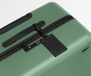 The Large suitcase in Sea Green shown shown from above highlighting TSA-approved combination lock and recycled leather luggage tag