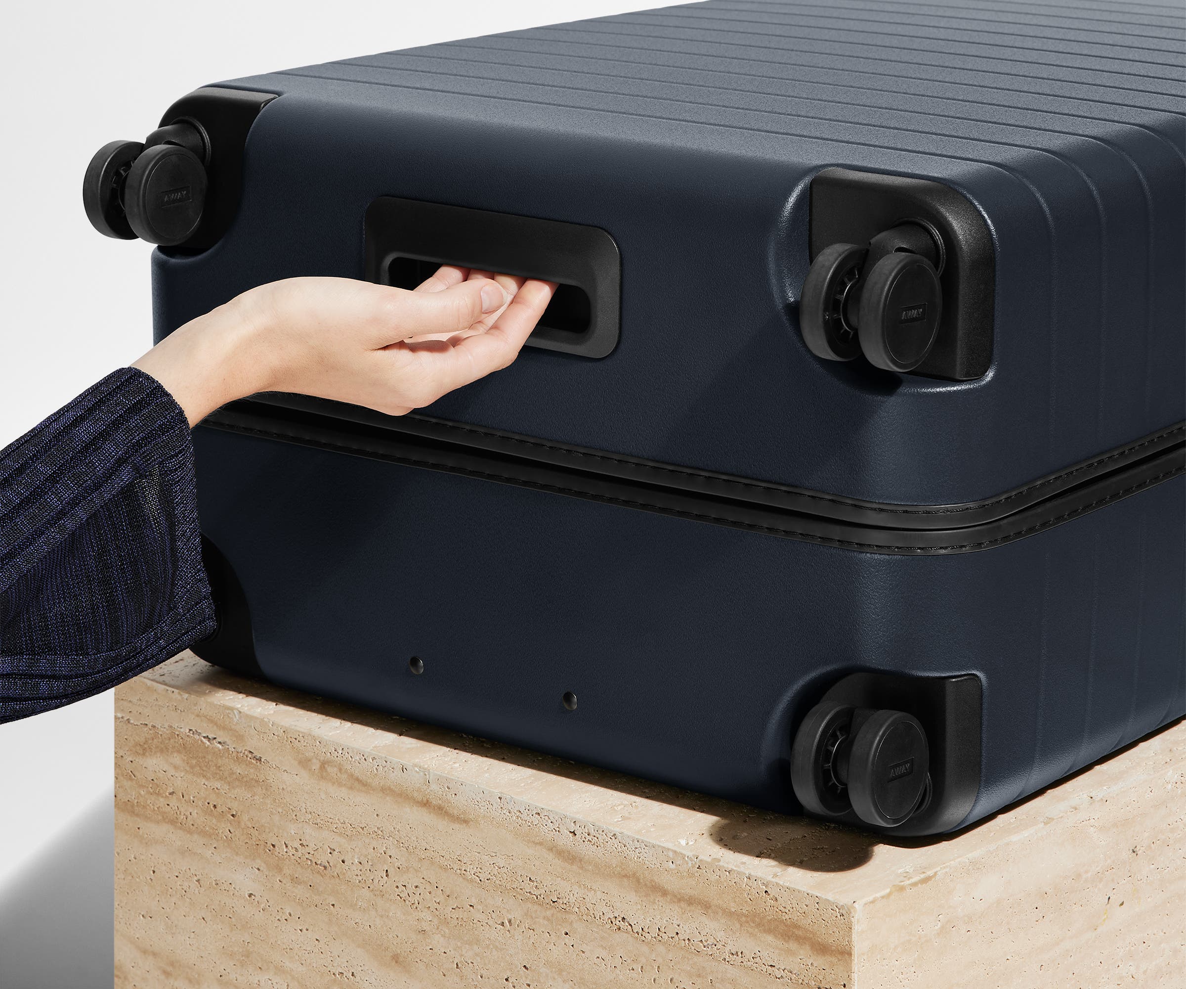 The Large suitcase in Navy Blue shown from below highlighting the underside grab handle