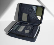 The Large suitcase in Navy Blue shown open on its side and packed with Away's packing organizers to show capacity and the interior compression system, designed to help you pack more in