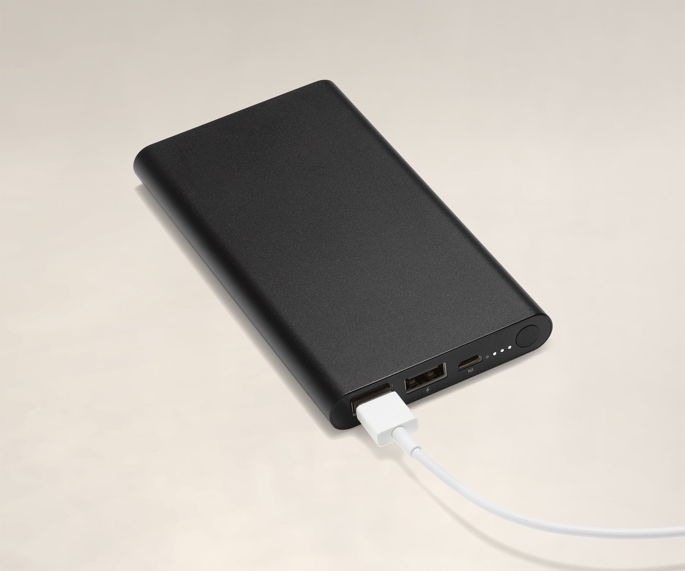 USB charger battery showing two USB-A ports, a micro-USB port, status lights, and a button to check the charge level. There is a white cable plugged into one USB port.