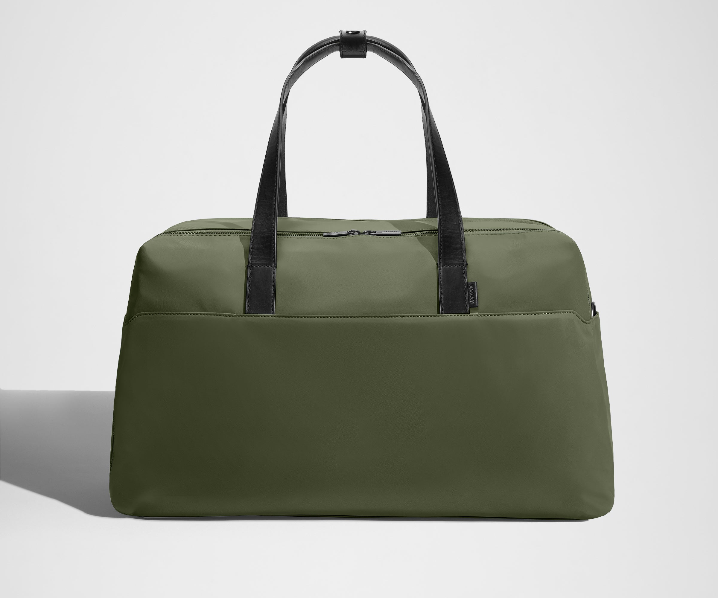 Green duffel bag with black straps on a light gray background