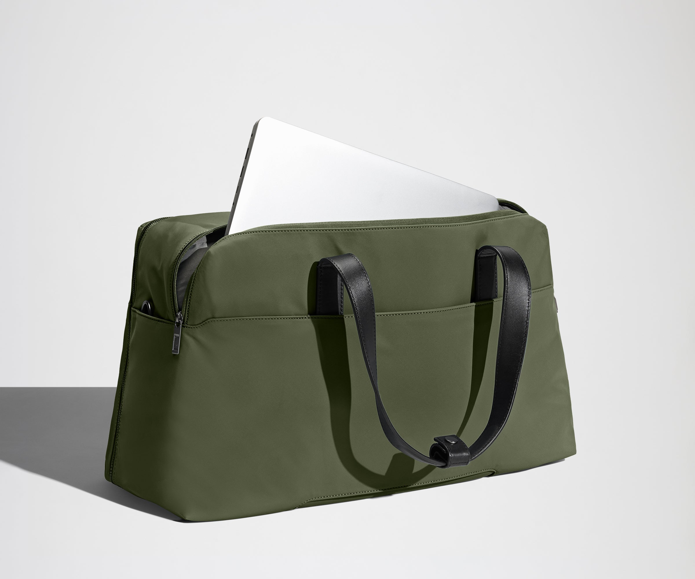 Laptop shown in the pocket of a green duffel bag