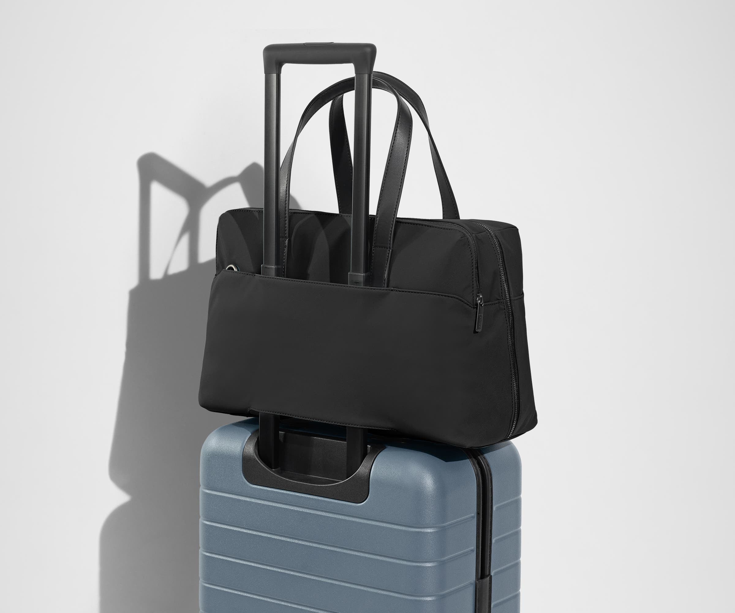 The Everywhere Bag secured to an Away suitcase by its trolley sleeve