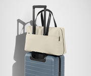 The Everywhere Bag secured to an Away suitcase by its trolley sleeve