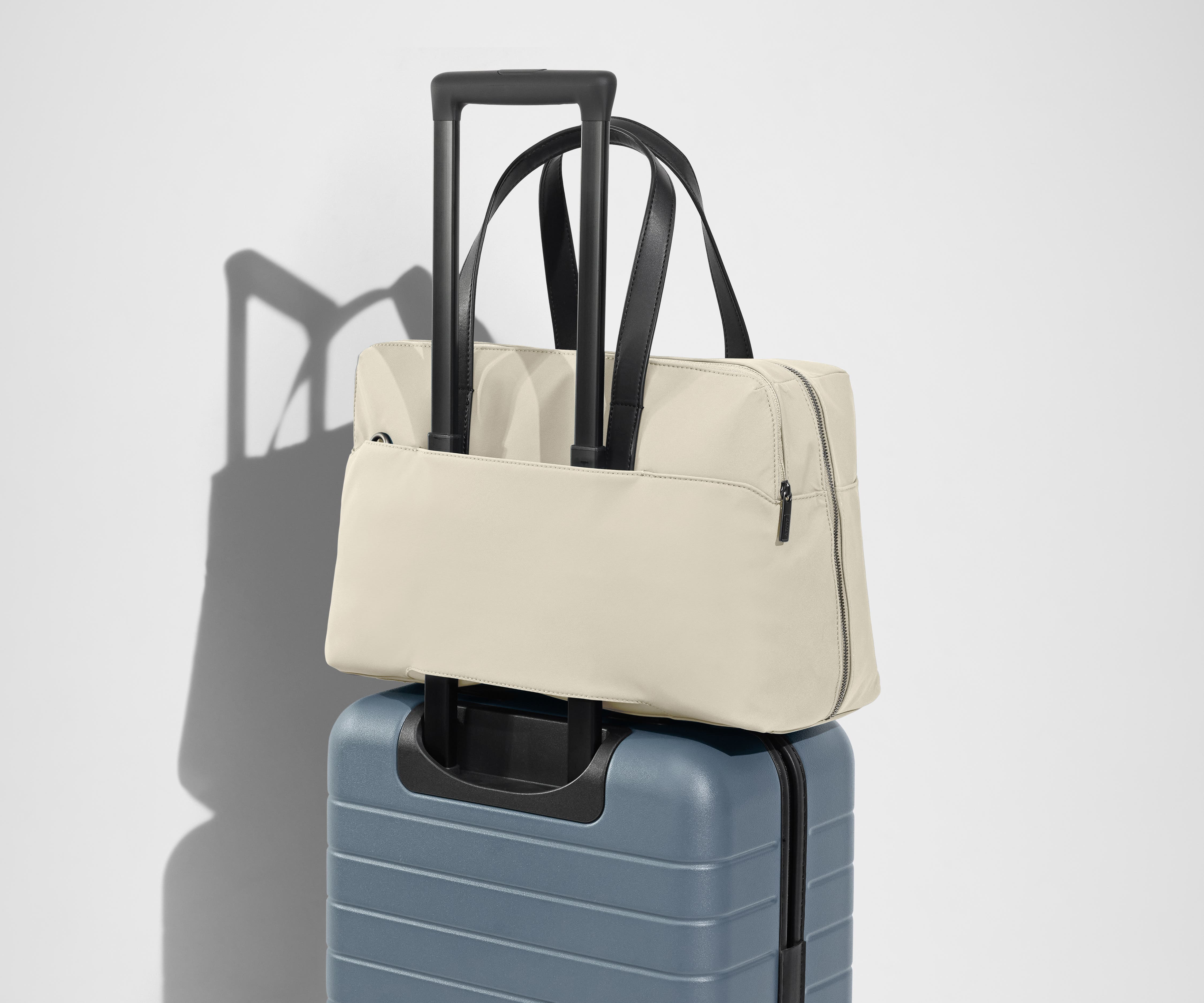 The Everywhere Bag secured to an Away suitcase by its trolley sleeve