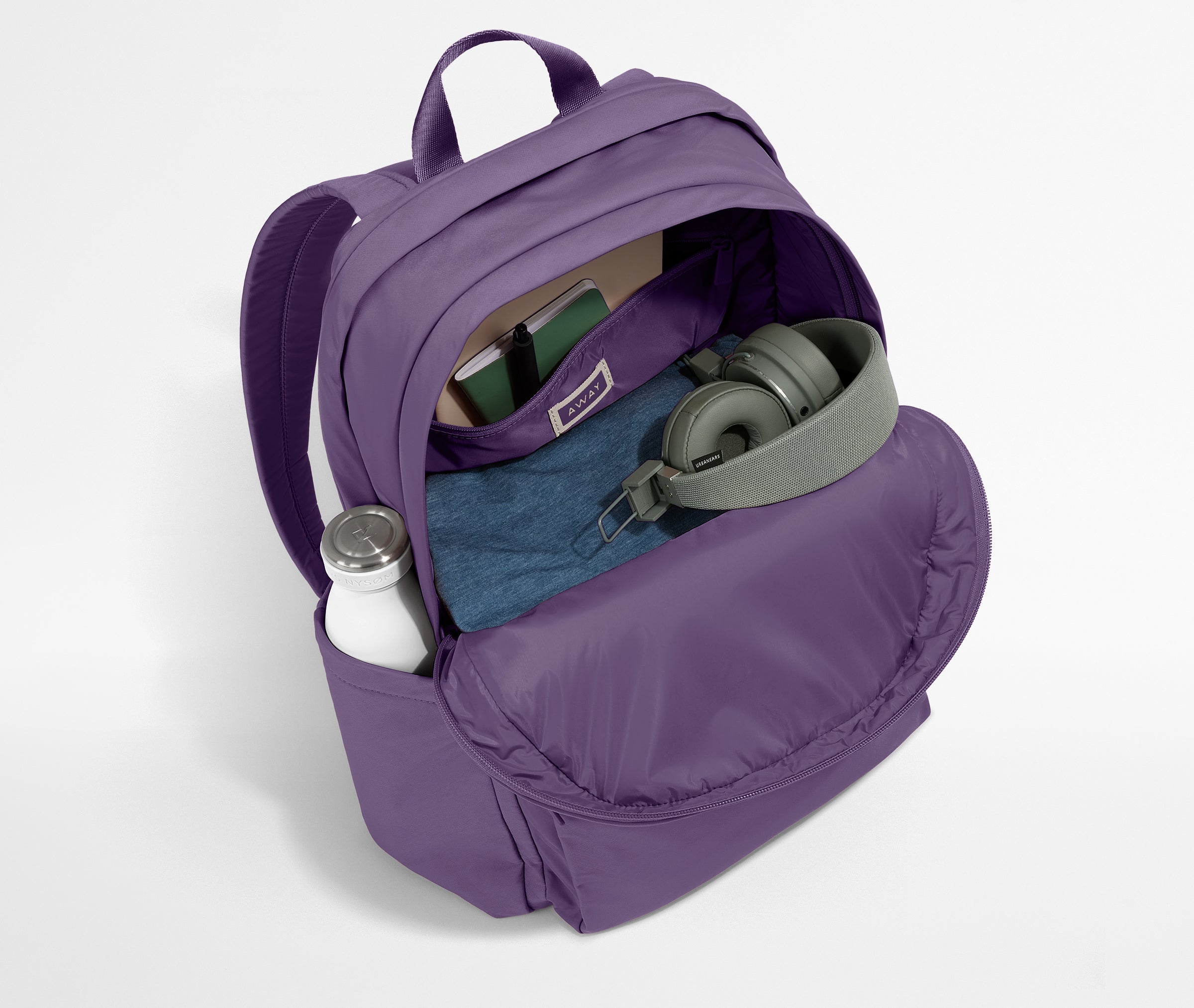 Front compartment packed with a notebooks, headphones, and clothing