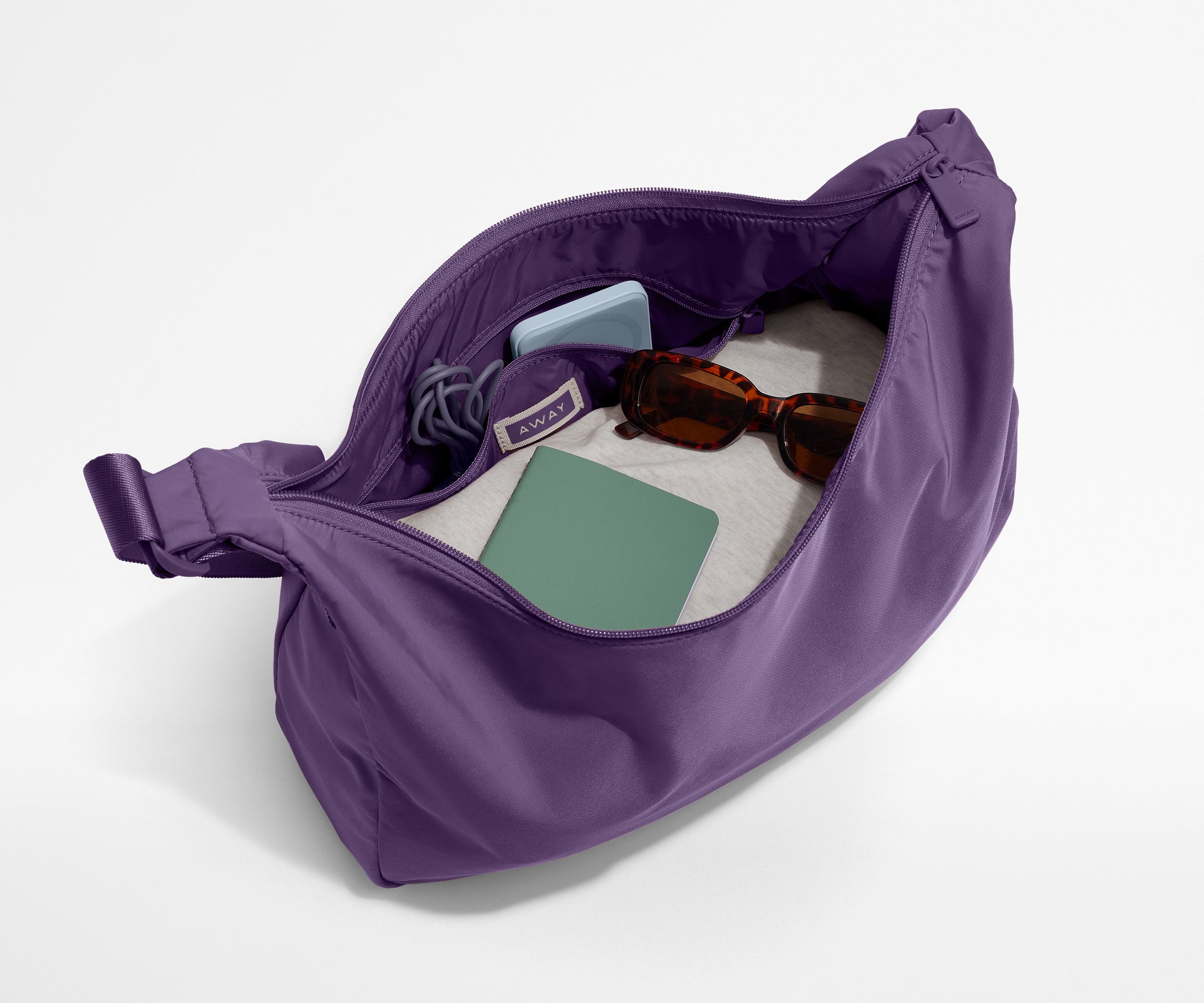 Featherlight crossbody packed with a sweater, notebook, sunglasses, and portable charger