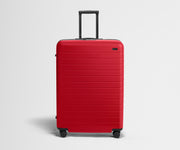 Red suitcase with a black handle on a light gray background
