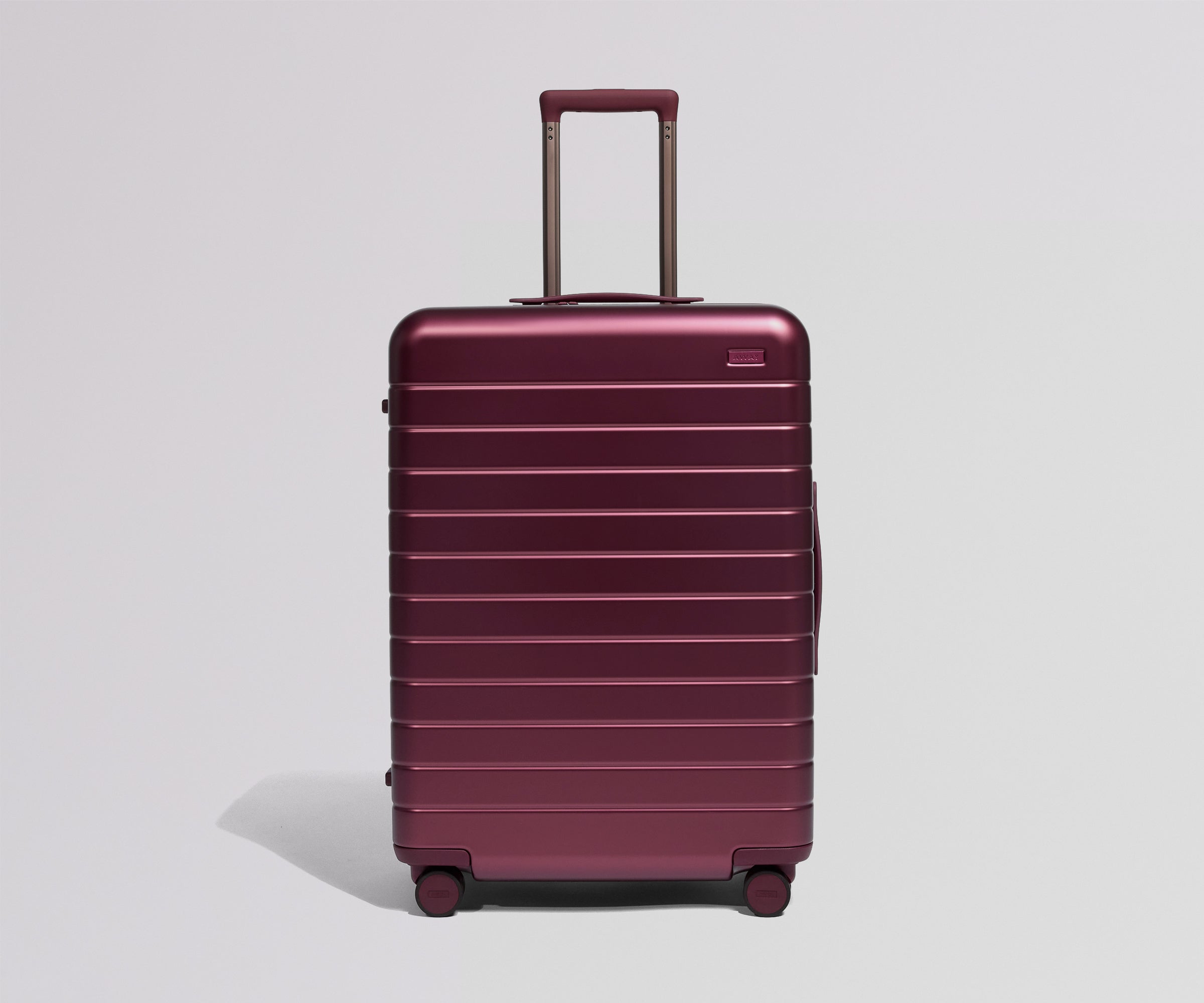 Maroon suitcase with a handle on a light gray background
