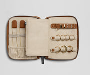 Zipped jewelry case with gold rings and tools on a light gray background