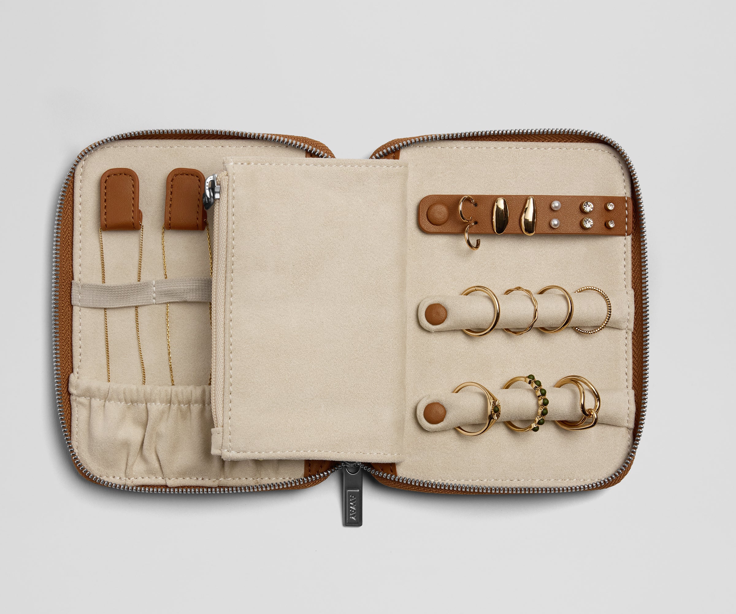 Zipped jewelry case with gold rings and tools on a light gray background