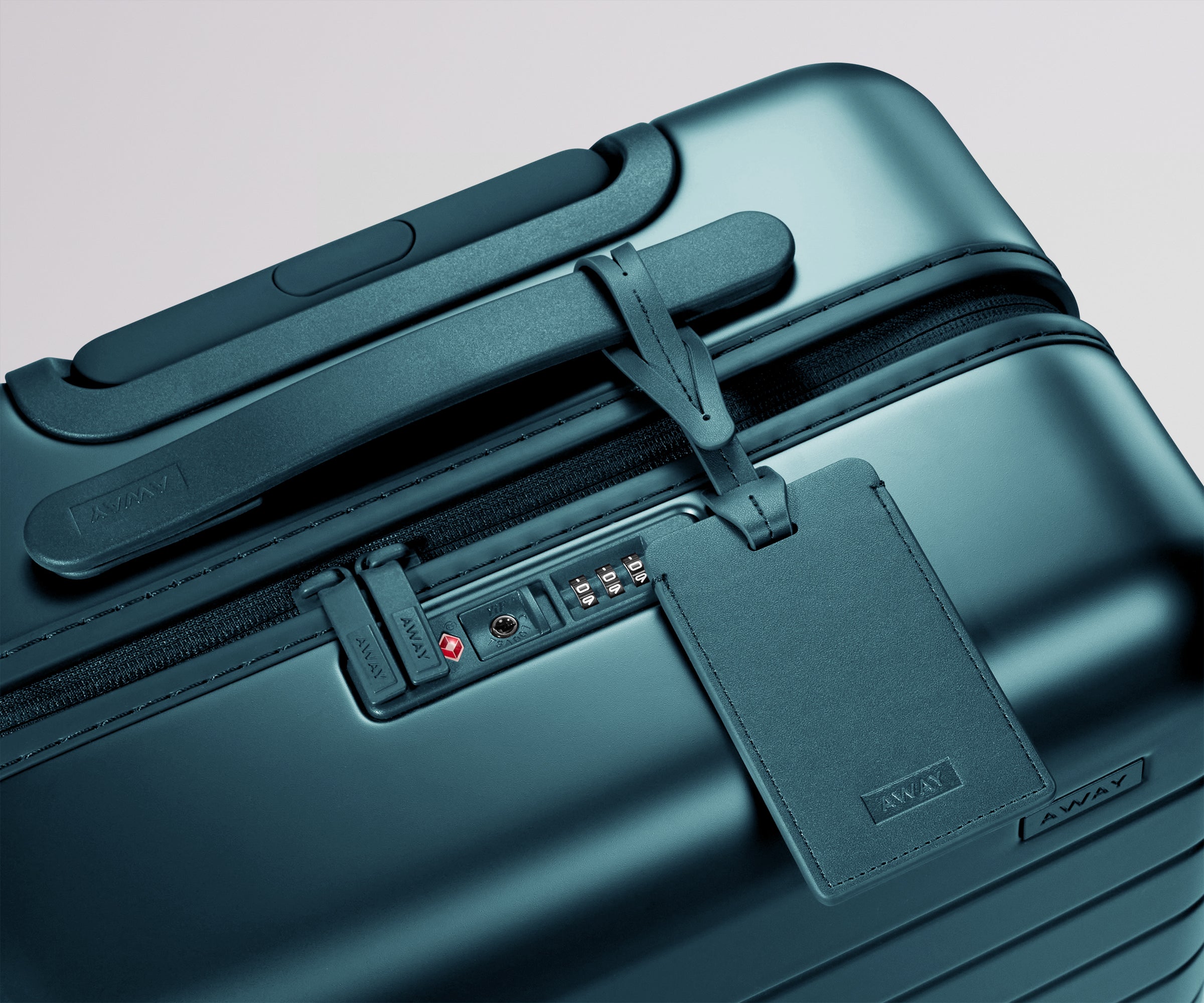 Teal suitcase with a matching leather luggage tag