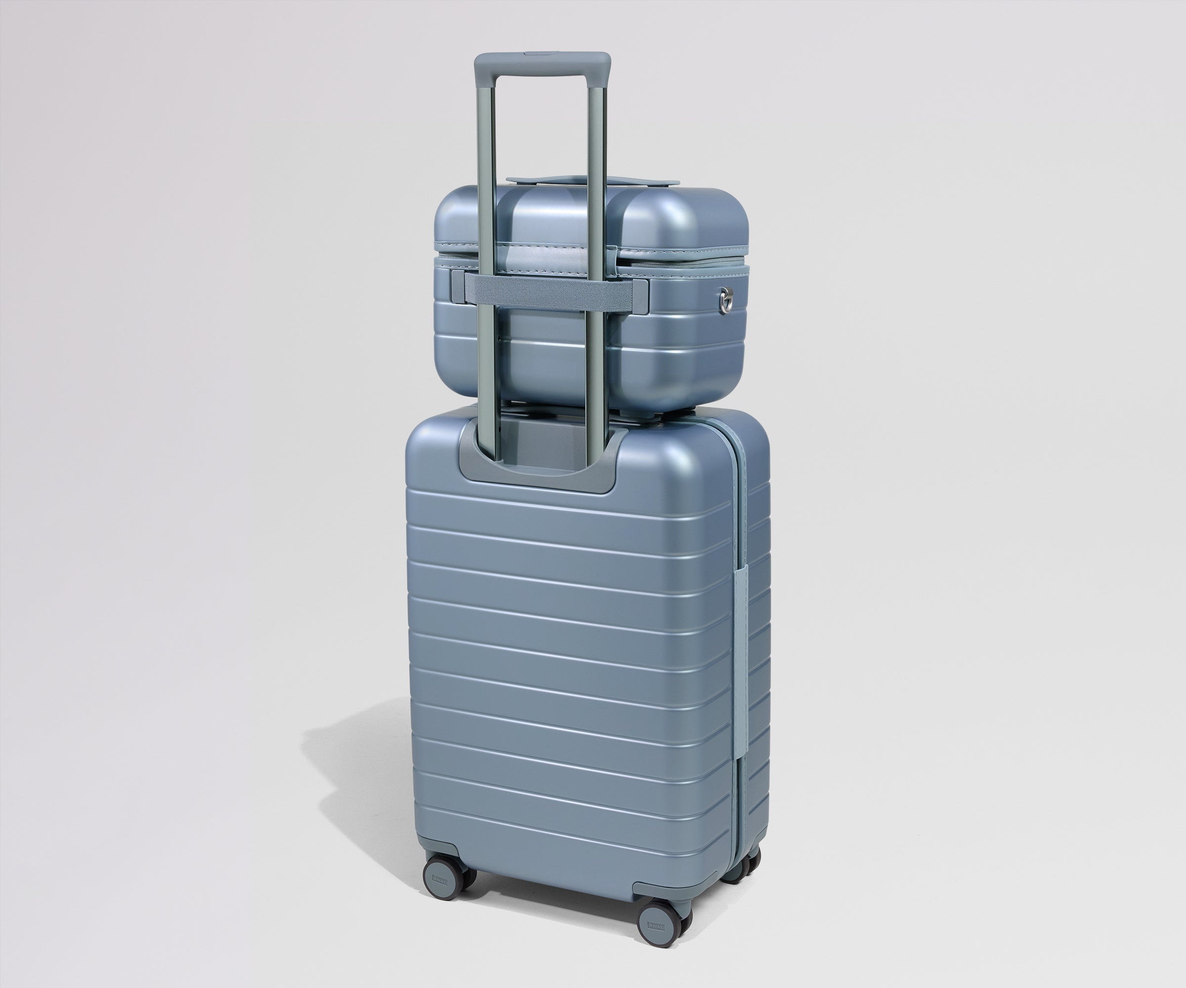 Two metallic blue suitcases stacked on a light gray background