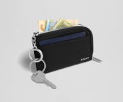 Black wallet with keys and money on a light gray background