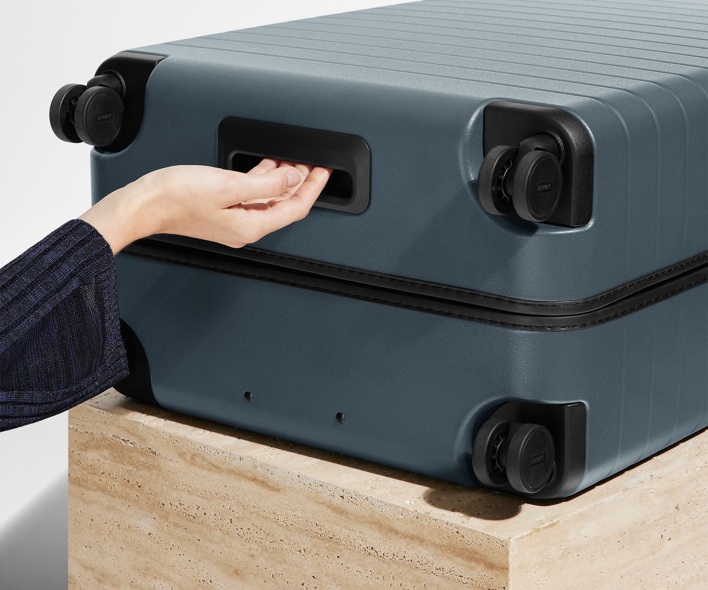 The Medium suitcase in Coast Blue shown from below highlighting the underside grab handle