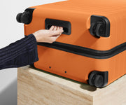 The Large suitcase in Sorbet Orange shown from below highlighting the underside grab handle