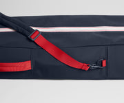 Navy bag with red strap and zipper on a light gray background