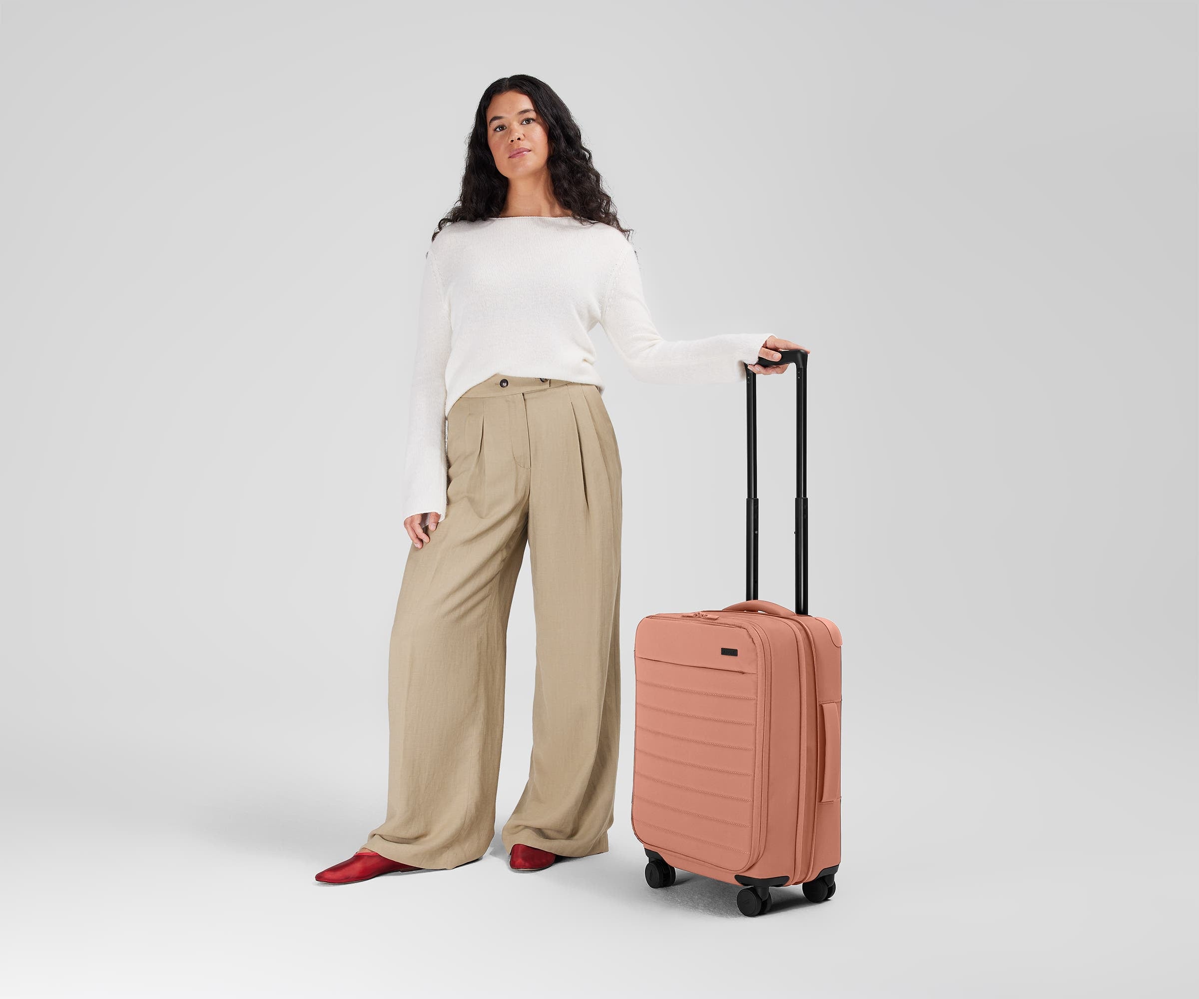 5'7" person standing next to the Softside Carry-on for scale