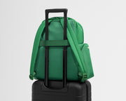 Green backpack attached to a black suitcase on a light gray background