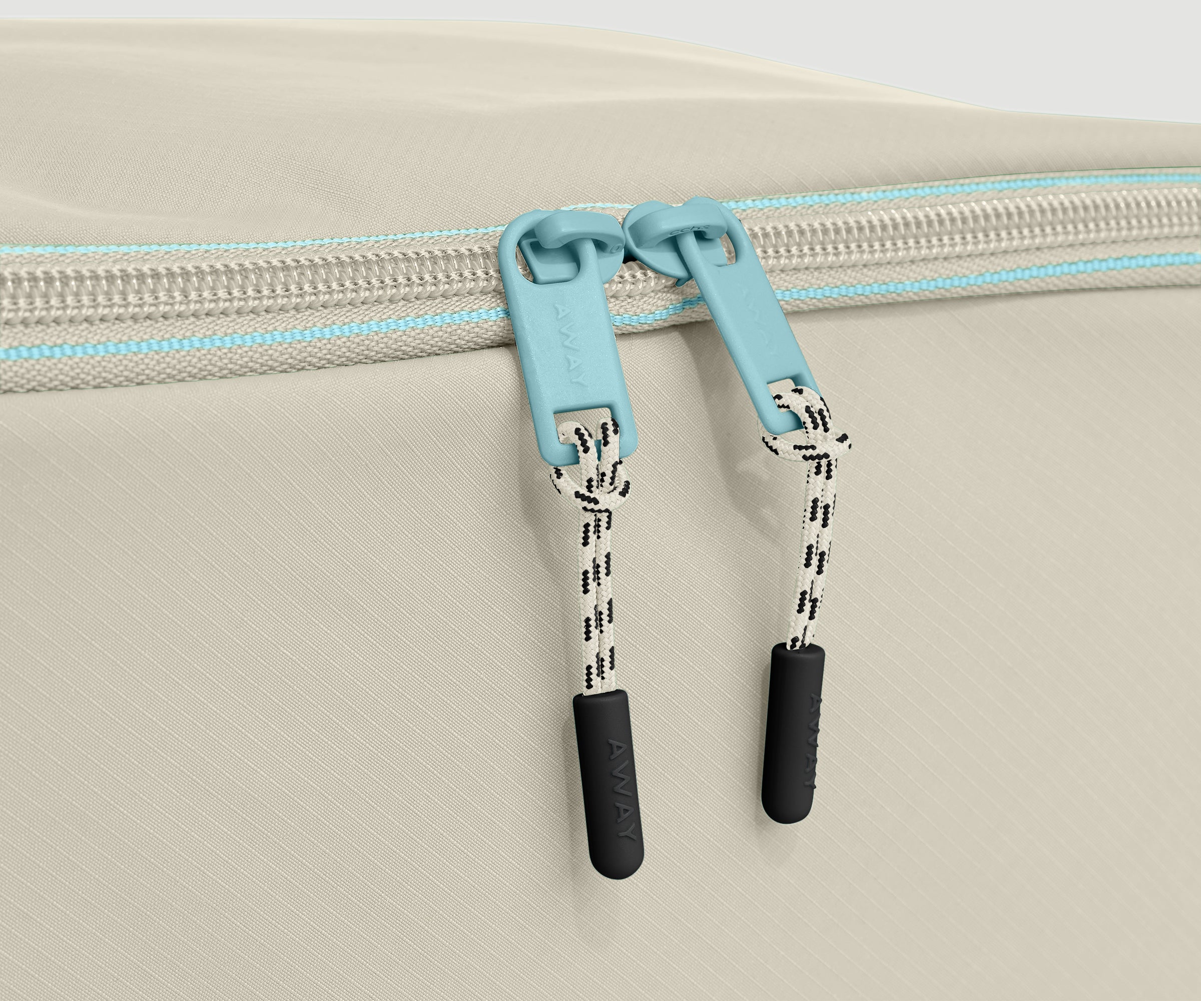 Close-up of a beige shoe cube with a blue zipper and black handles on a light gray background