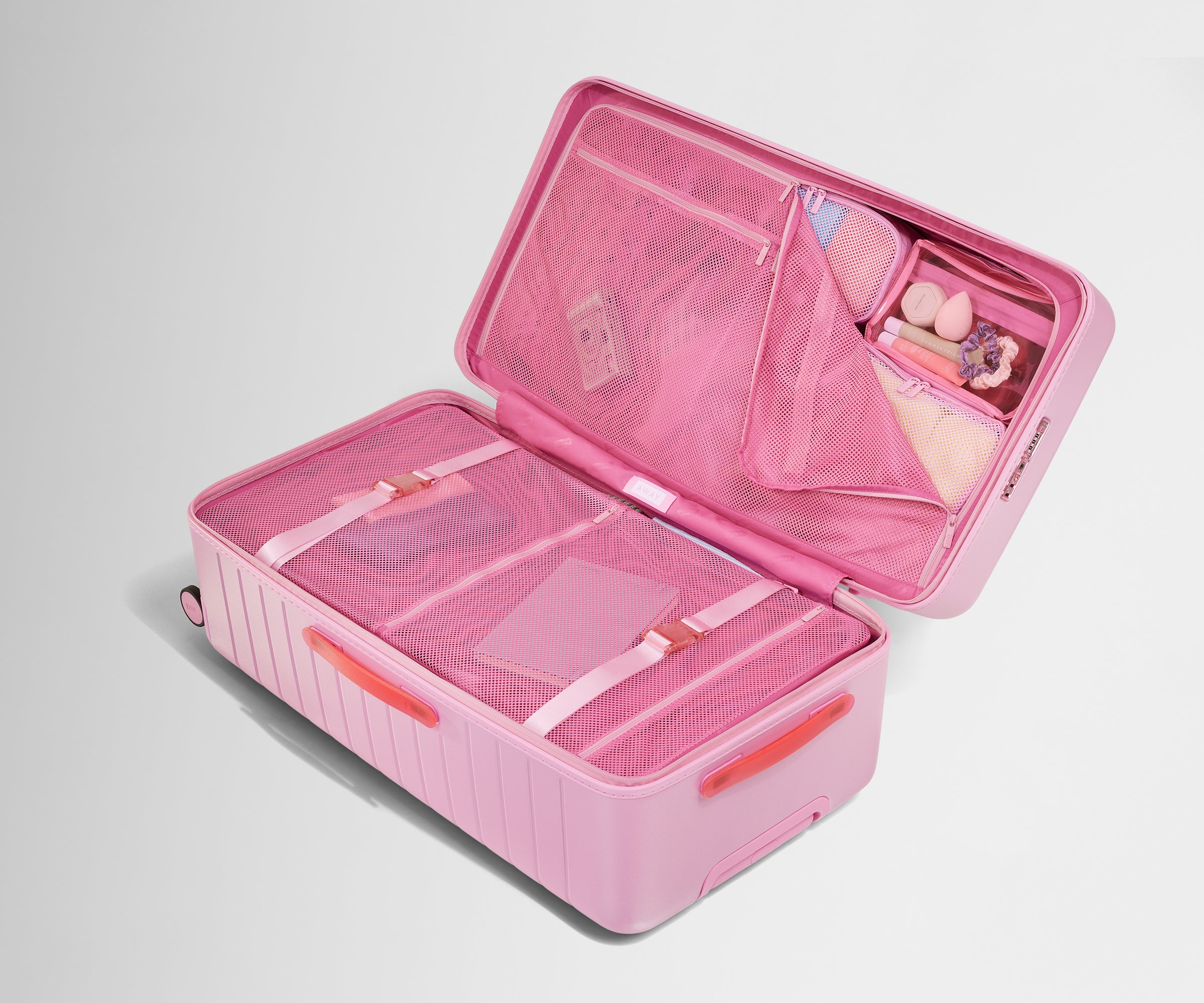 The Trunk suitcase in Hot Pink shown open on its side and packed with Away's packing organizers to show capacity and the interior compression system, designed to help you pack more in