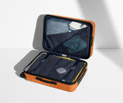 The Bigger Carry-On suitcase in Sorbet Orange shown open on its side and packed with Away's packing organizers to show capacity and the interior compression system, designed to help you pack more in