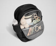 Front main compartment packed with child essentials, including a stuffed animal, wipes, and change of clothes