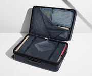 The Large Flex suitcase in Navy Blue shown open on its side and packed with Away's packing organizers to show capacity and the interior compression system, designed to help you pack more in