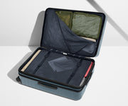 The Large Flex suitcase in Coast Blue shown open on its side and packed with Away's packing organizers to show capacity and the interior compression system, designed to help you pack more in