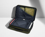 The Bigger Carry-On Flex suitcase in Olive Green shown open on its side and packed with Away's packing organizers to show capacity and the interior compression system, designed to help you pack more in
