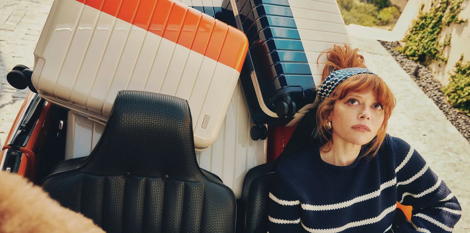 Natasha Lyonne in a convertible with Away x La Ligne suitcases piled in the backseat