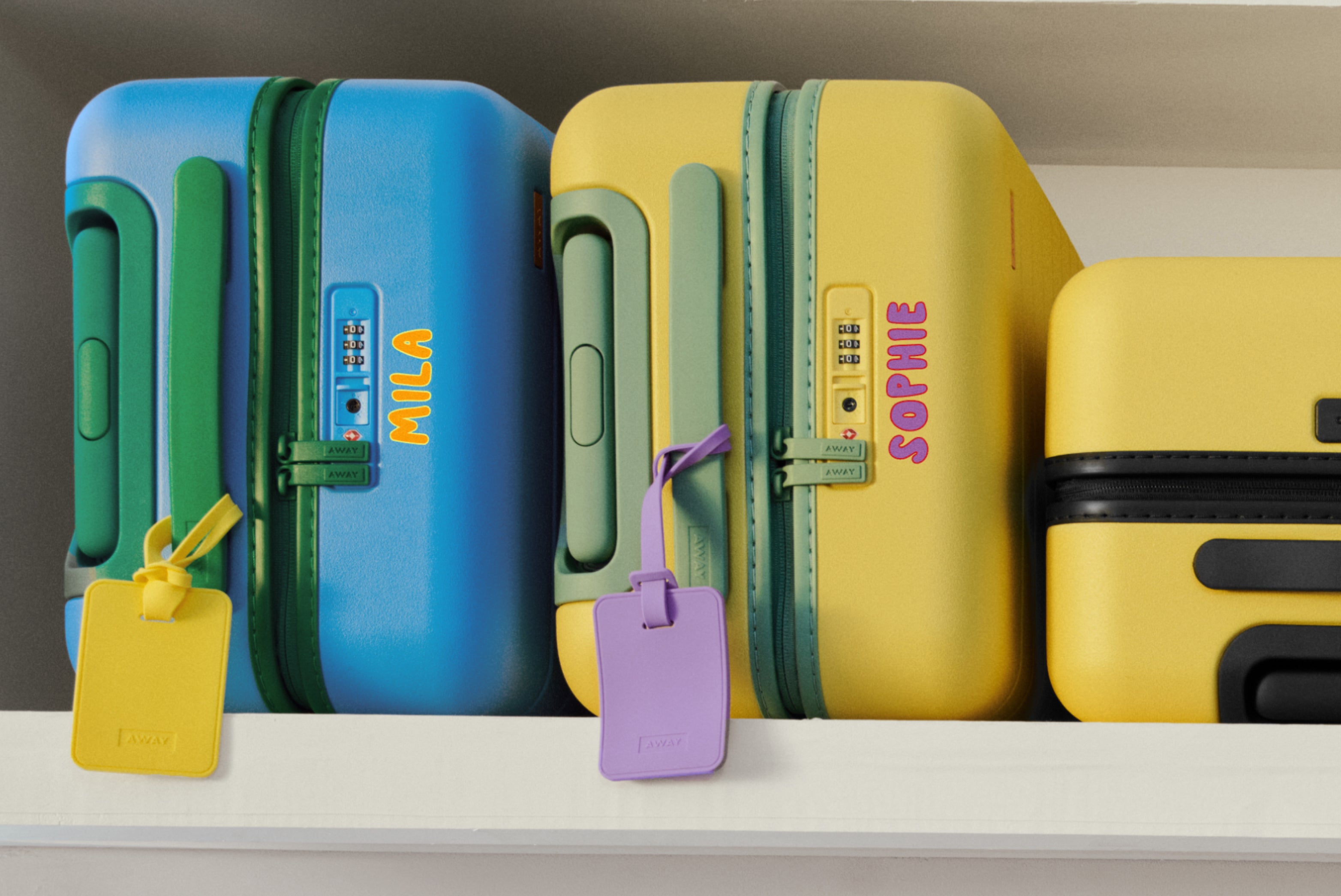 The Kids Carry-On in Splash Blue and The Kids Carry-On in Sunshine Yellow personalized in an airplane overhead bin. 