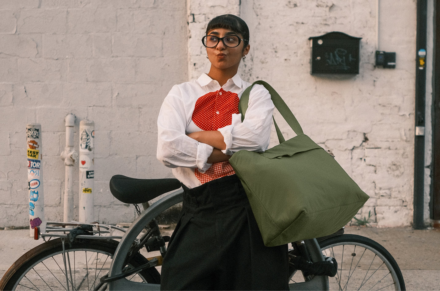 Person holding a green bag with a bicycle in an urban setting