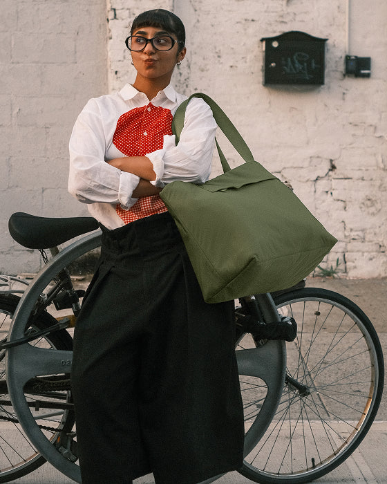 Person holding a green bag with a bicycle in the background