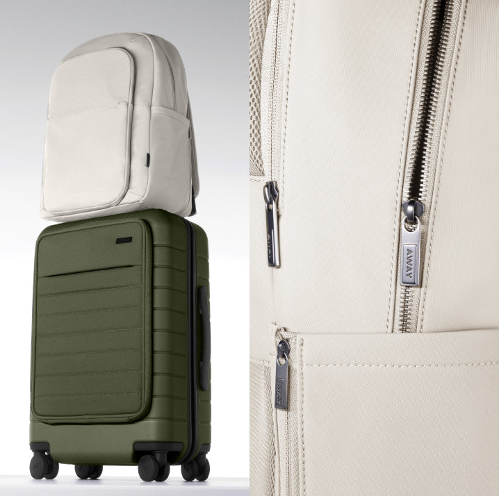 Green suitcase with a beige backpack on top, next to a beige bag with zippers.