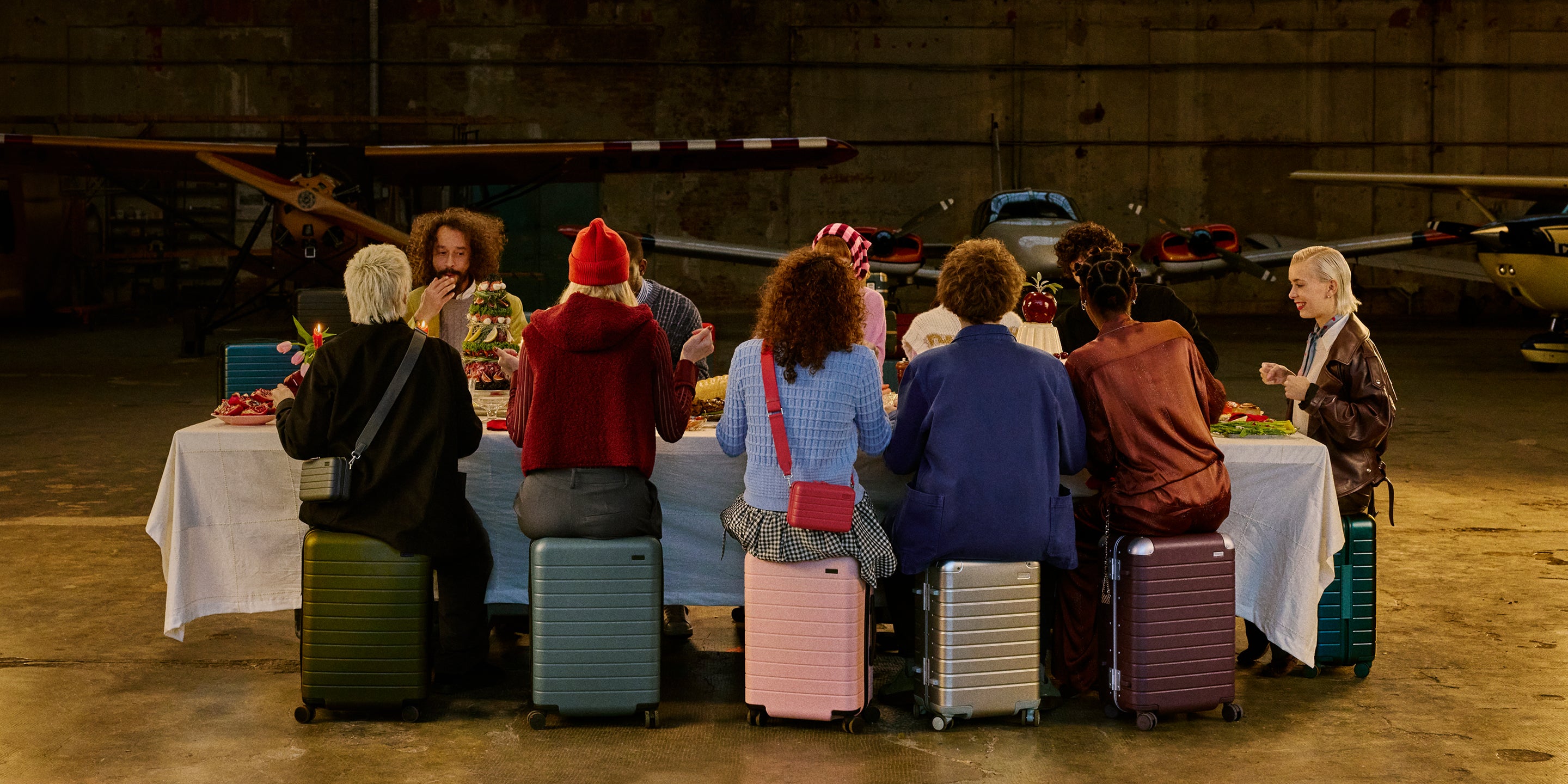 Travelers sitting on their Away luggage at a feast. 