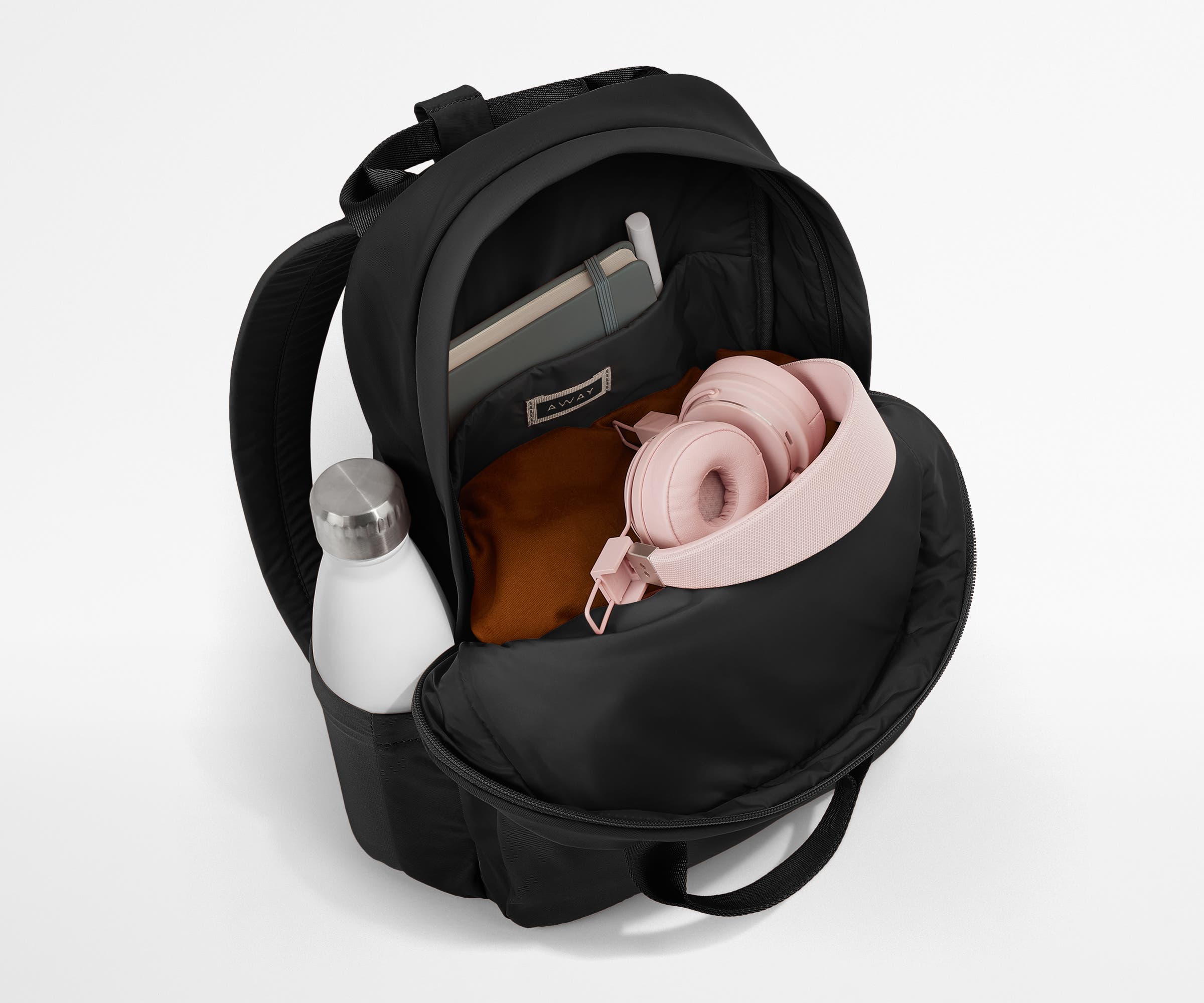Featherlight Backpack packed with a sweater, notebook, headphones, and water bottle