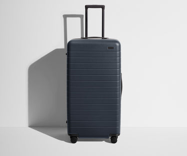Front product view of The Trunk suitcase in Navy Blue with raised handle