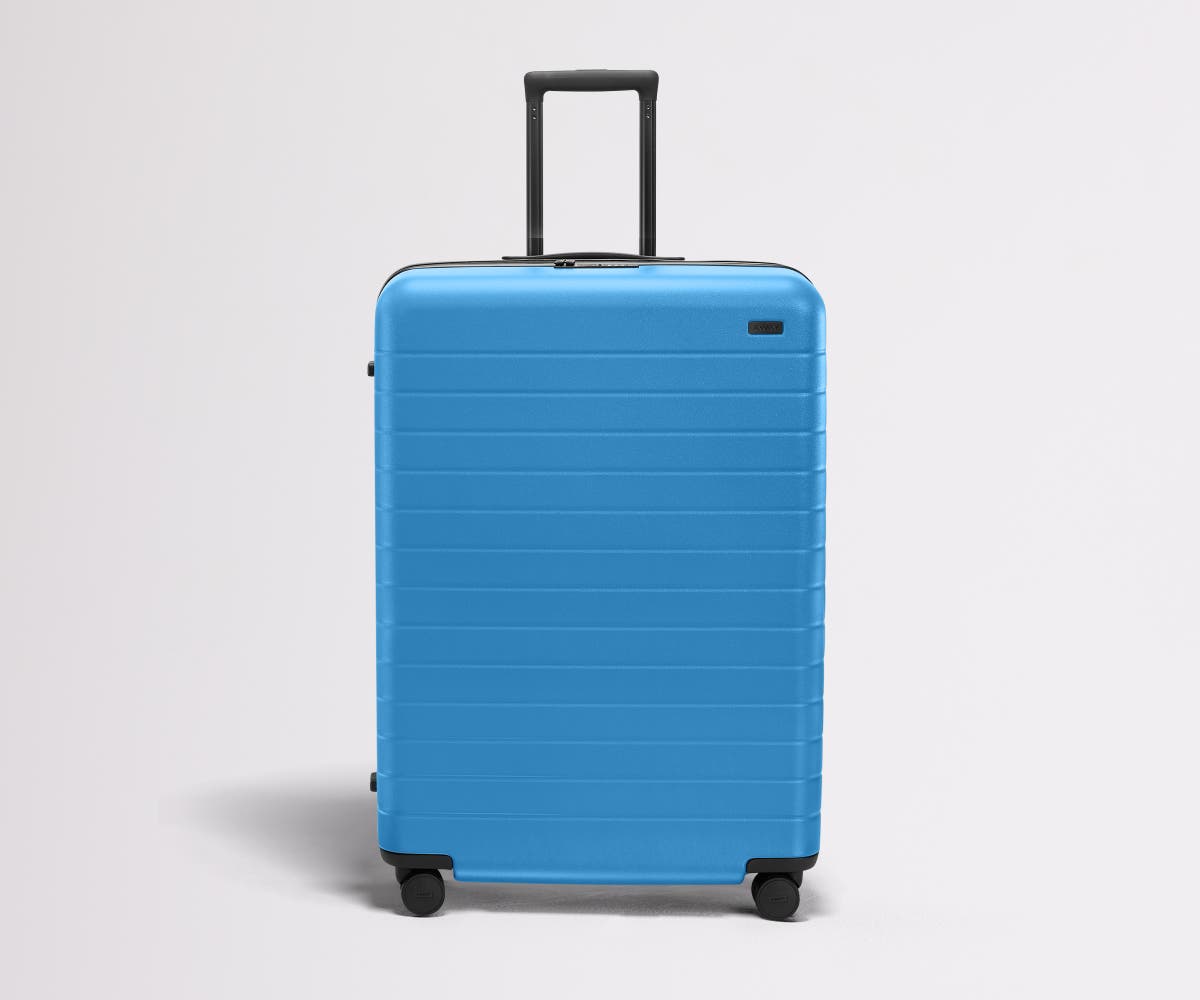 Front product view of The Large Flex suitcase in Splash Blue with raised handle