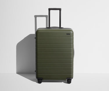 Front product view of The Medium suitcase in Olive Green with raised handle
