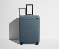 Front product view of The Medium suitcase in Coast Blue with raised handle