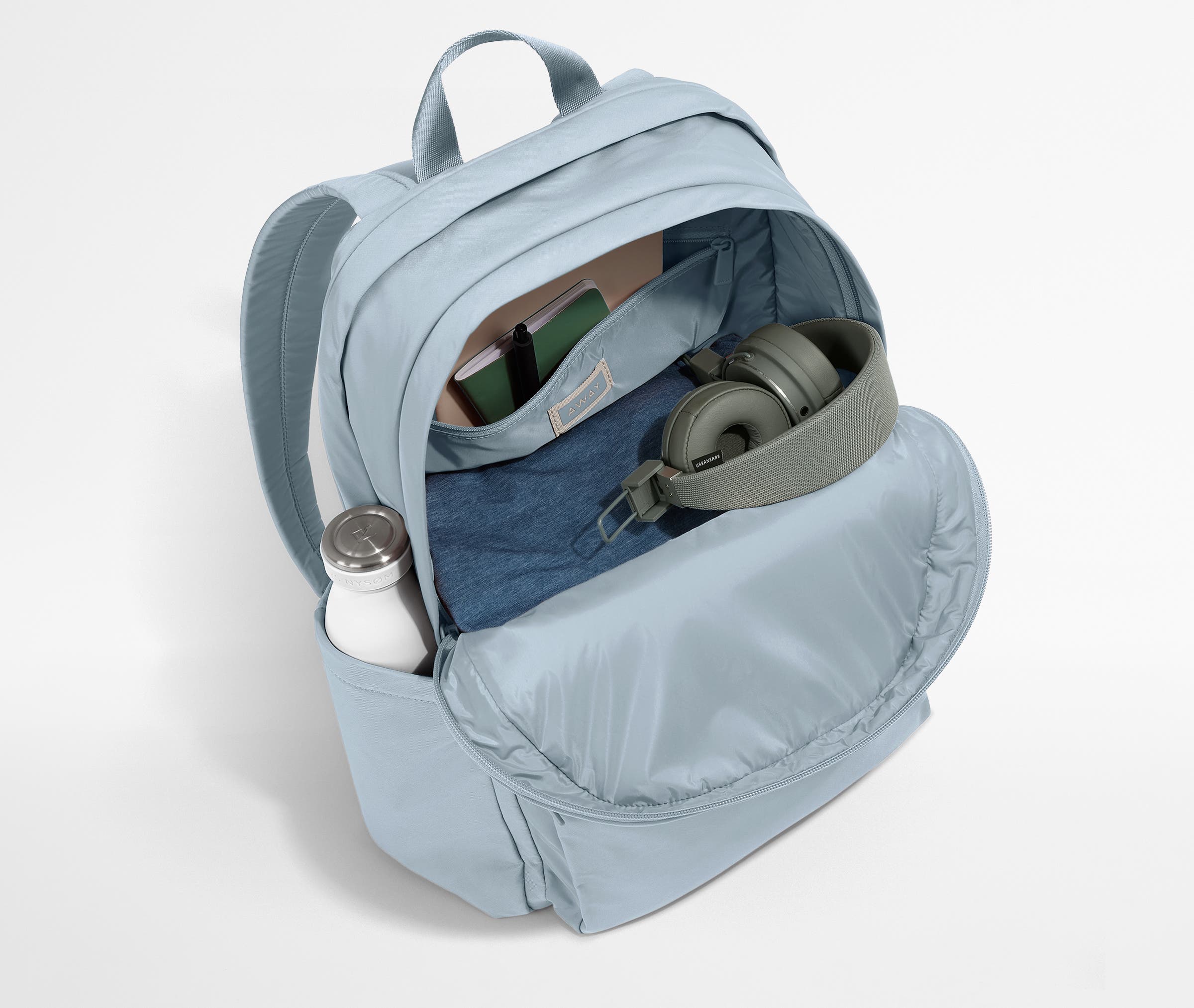 Front compartment packed with a notebooks, headphones, and clothing