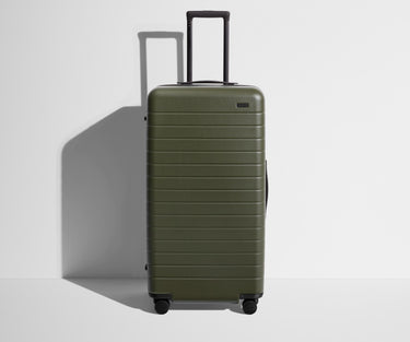 Front product view of The Trunk suitcase in Olive Green with raised handle