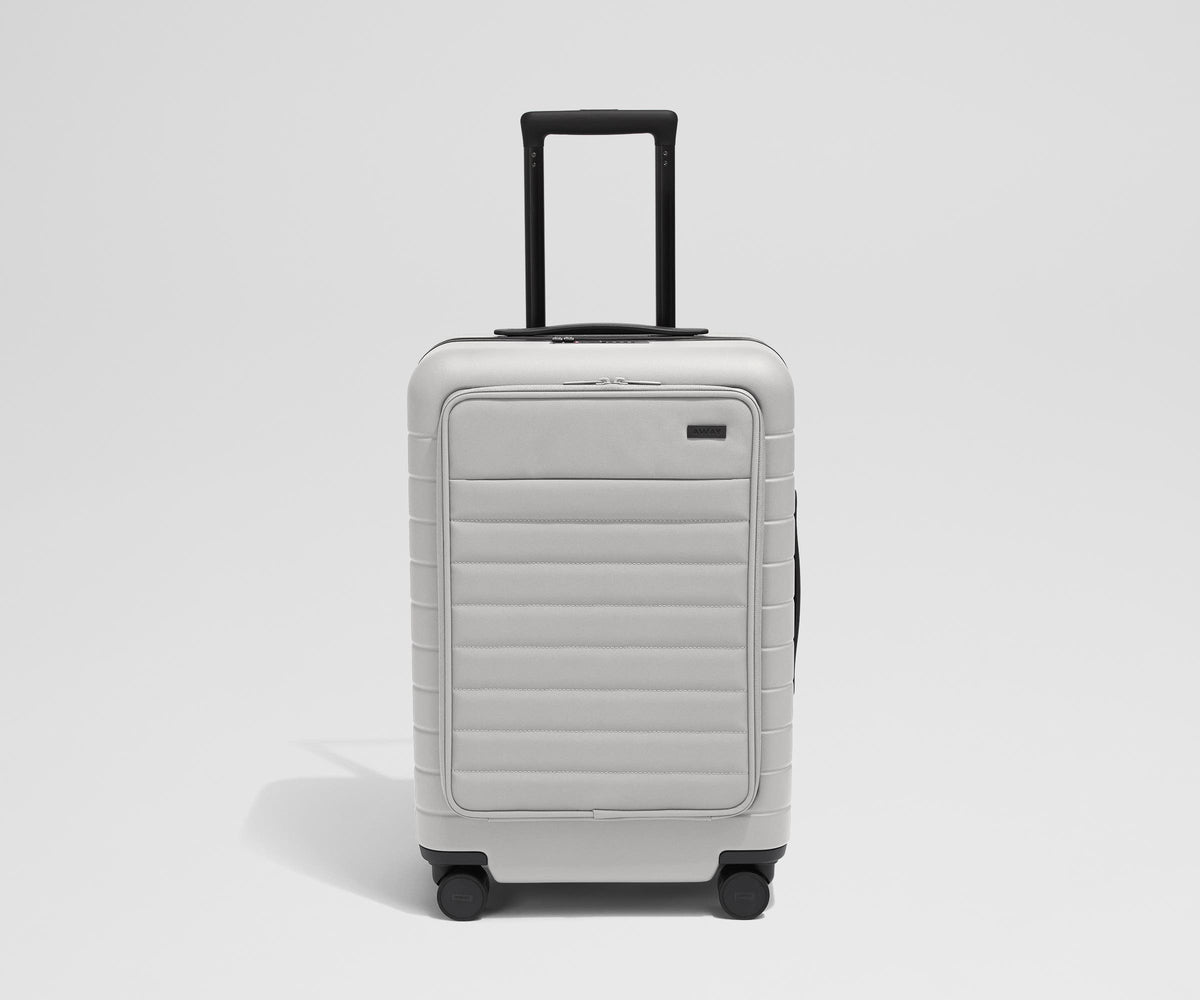 Front product view of The Front Pocket Bigger Carry-On suitcase in Cloud Gray with raised handle