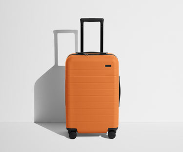 Front product view of The Carry-On suitcase in Sorbet Orange with raised handle