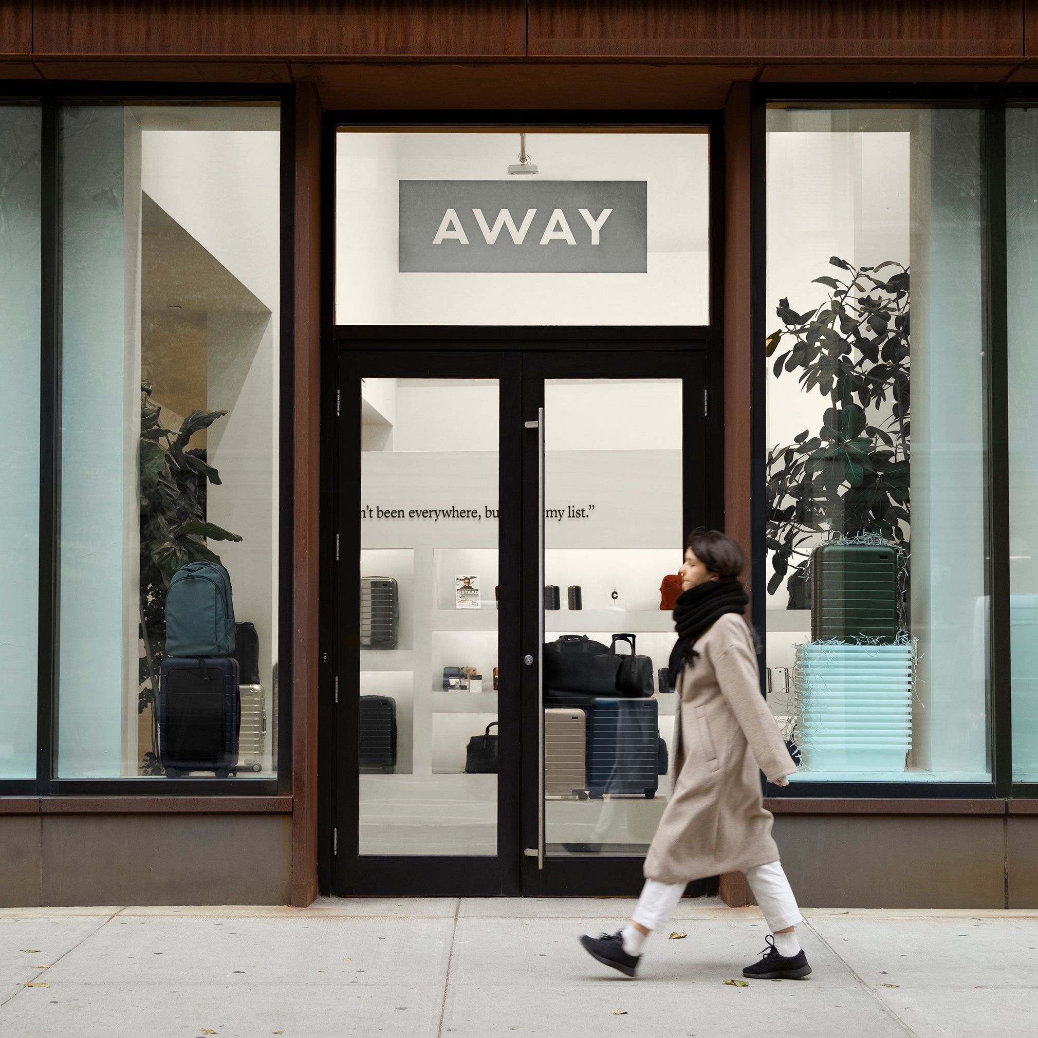 Photo of a woman walking past an Away travel store