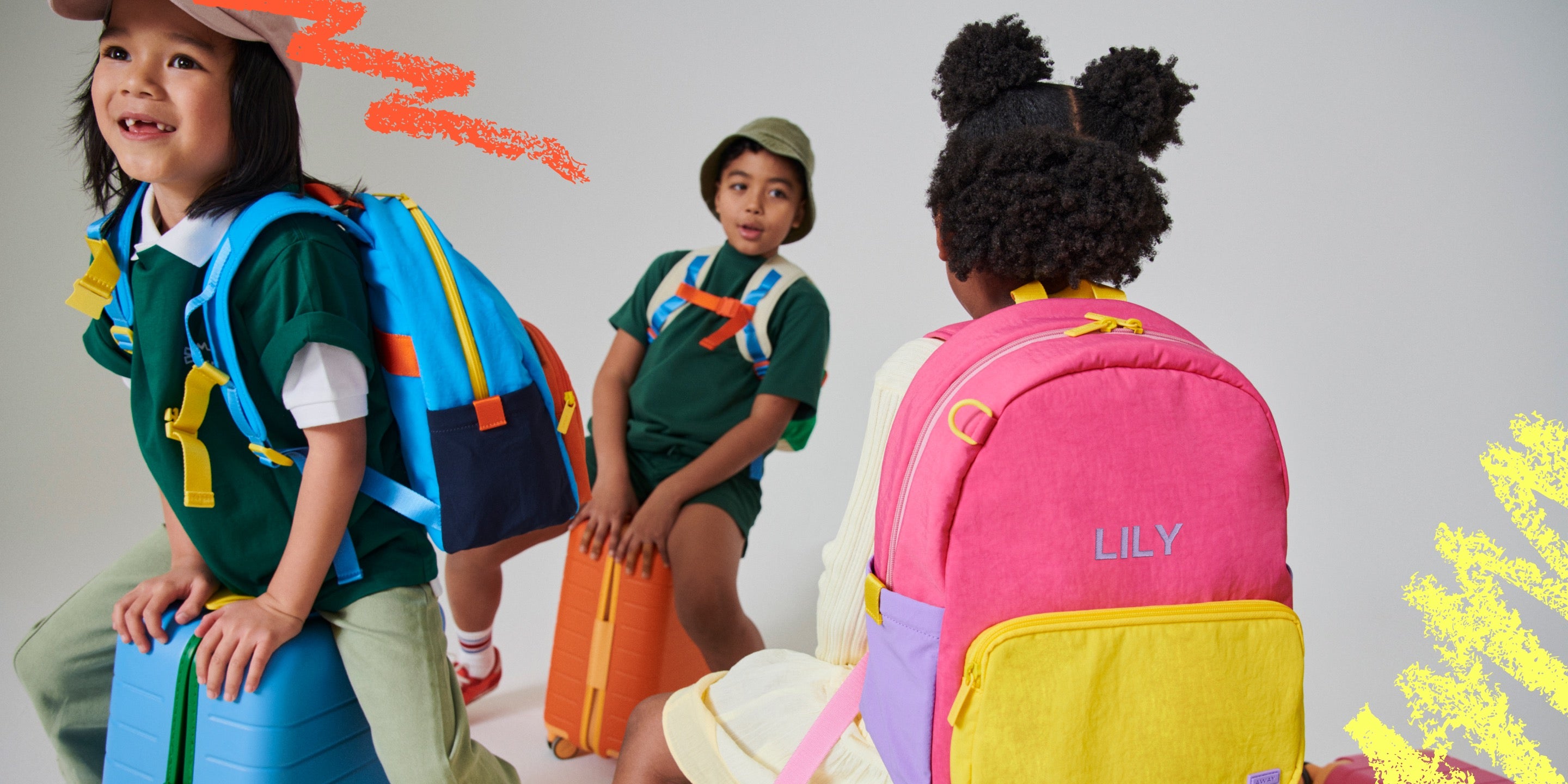 Kids on top of their Away Kids Carry-On suitcases while wearing Kids Backpacks