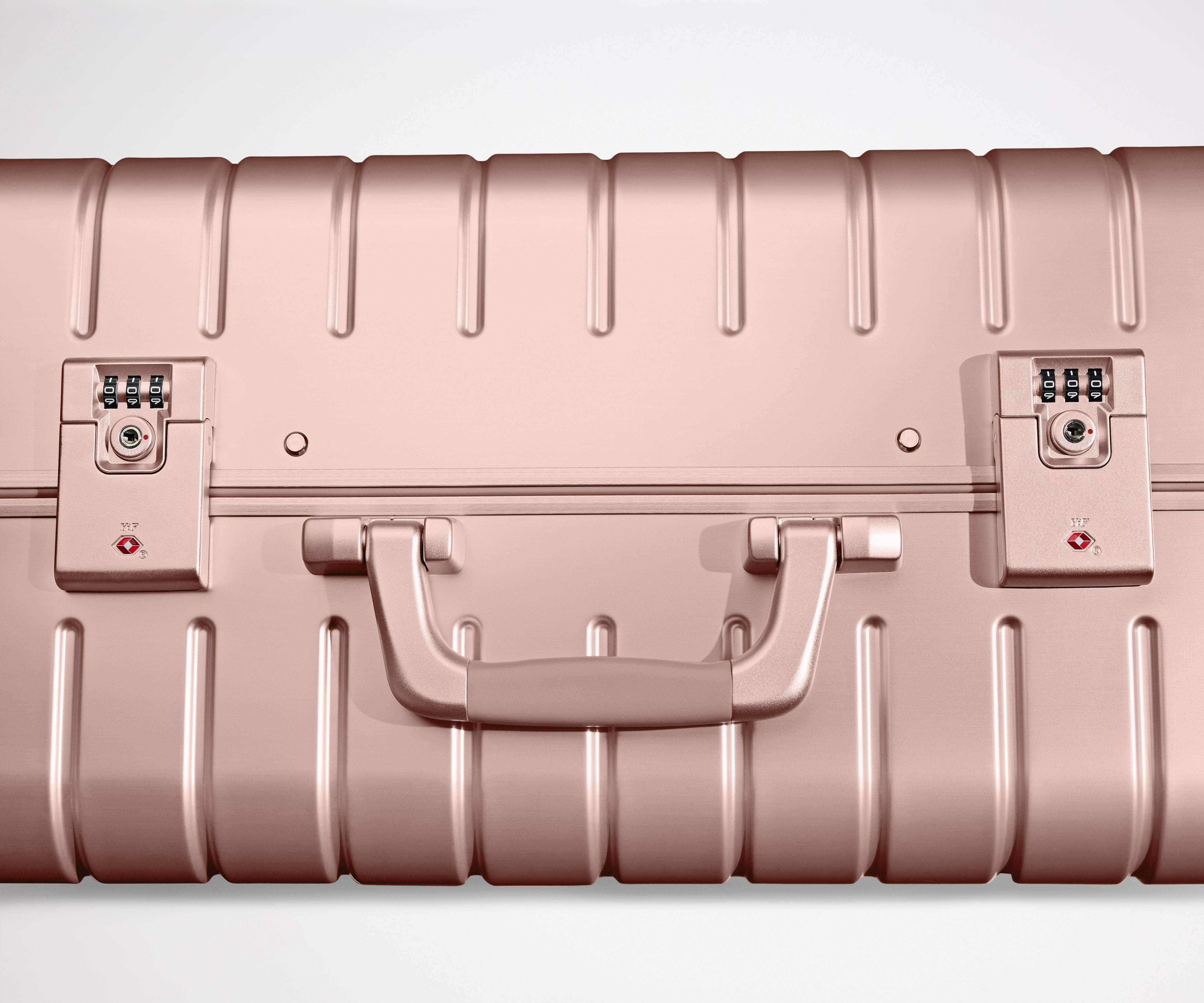 Close-up view of the dual-TSA locks on a Rose Gold Aluminum suitcase