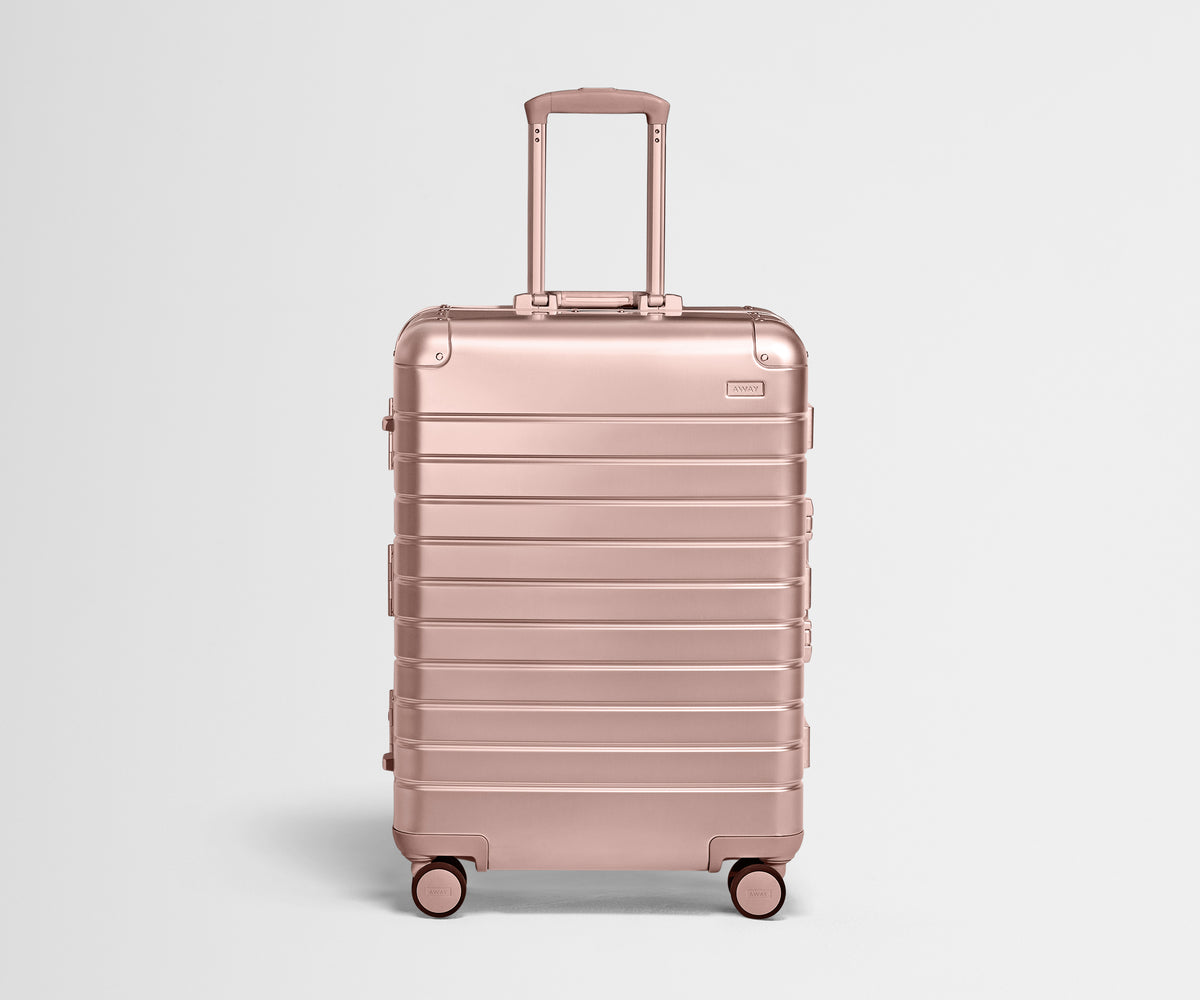 Front view of the Medium: Aluminum suitcase in Rose Gold with handles raised
